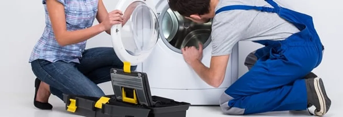 Washer repair technician inspecting a front-load washing machine with tools in Duluth, MN
