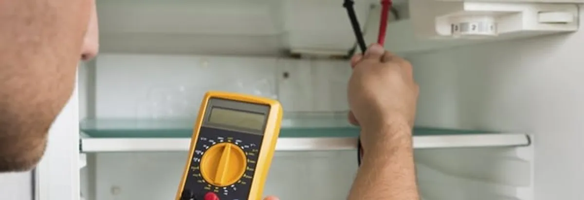 Refrigerator repair technician testing electrical components with a multimeter in Duluth, MN