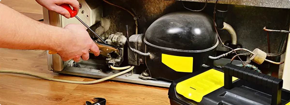 Refrigerator repair technician fixing the compressor and wiring in Duluth, MN